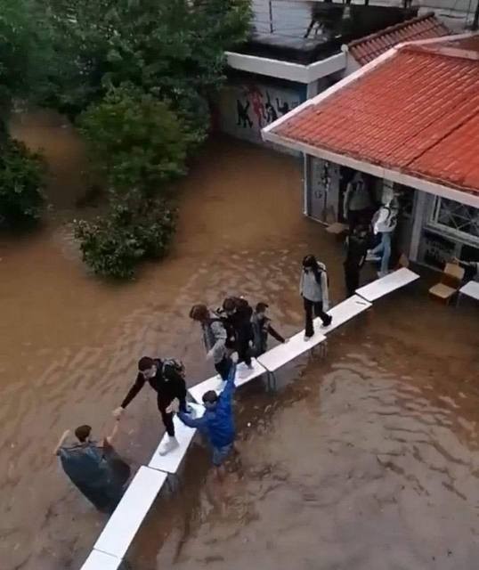 Μαθητές περπατούν πάνω σε θρανία για να φύγουν από πλημμυρισμένο σχολείο